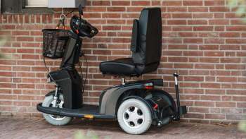 An electric mobility scooter positioned against a brick wall.