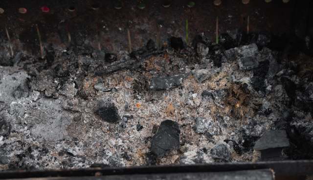 Ash and charcoal remnants in a grill.
