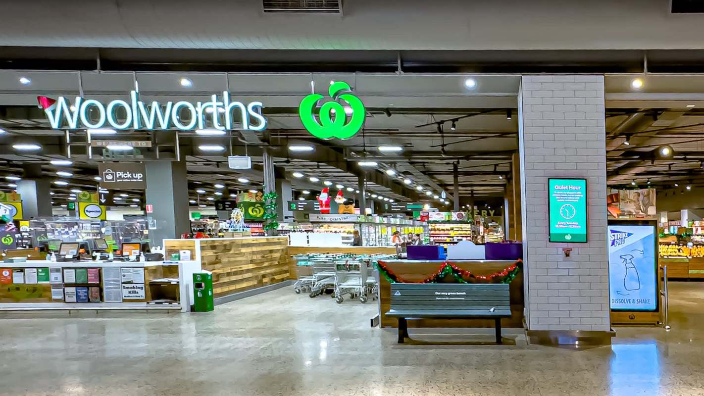 A Woolworths supermarket interior featuring shopping carts, displays, and a sign for Quiet Hour.