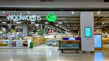 A Woolworths supermarket interior featuring shopping carts, displays, and a sign for Quiet Hour.
