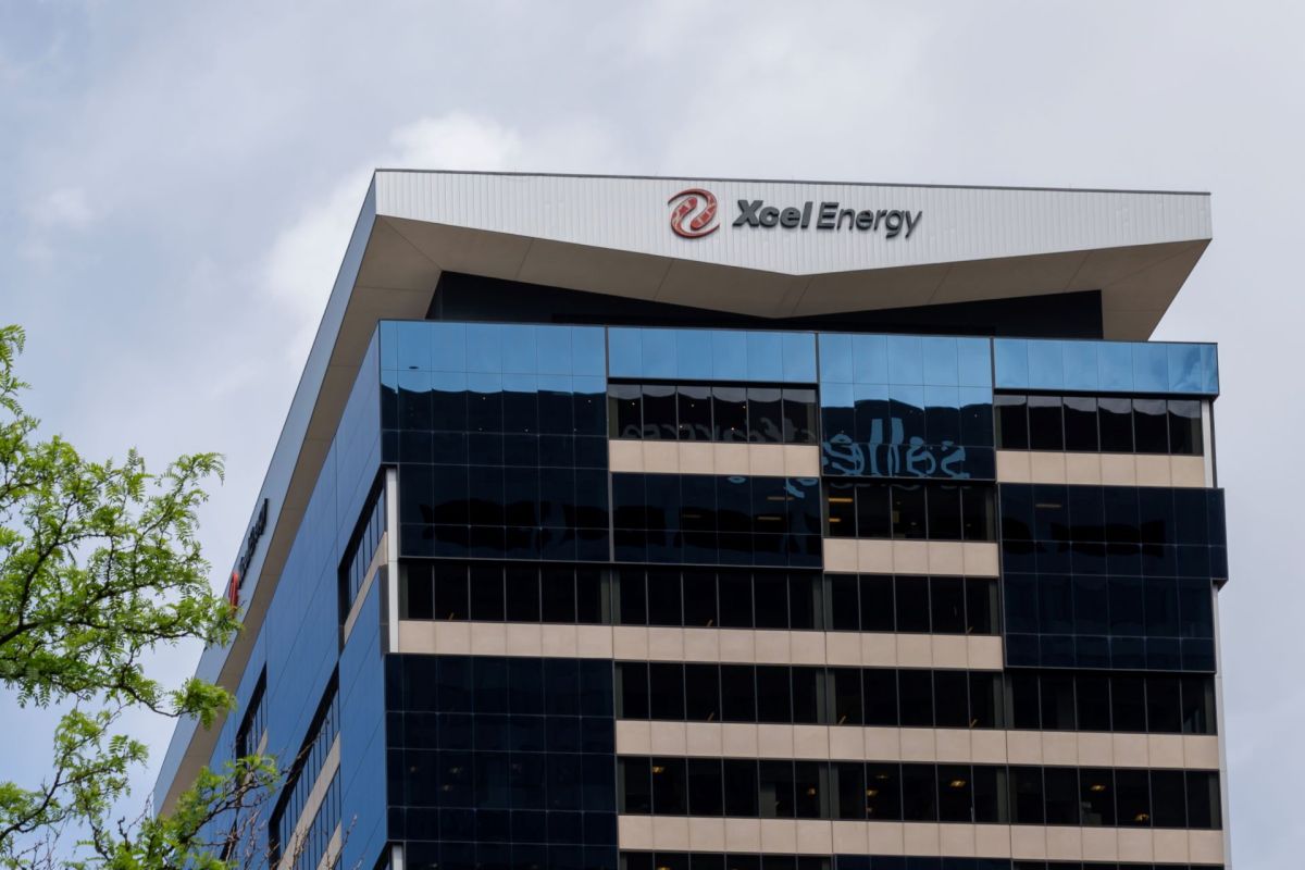 An office building with the Xcel Energy logo on the roof and reflective blue glass windows.