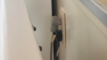 A power outlet with two cables plugged into it, partially obscured by furniture.